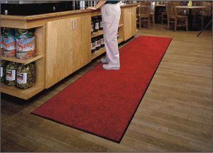 Man standing on a long Tri Grip floor mat runner in front of a food service counter