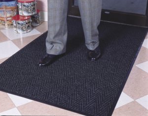 Man standing on Chevron indoor entrance mat placed inside main entrance to a retail store on a hard floor surface
