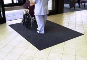 Wheelchair and nurse crossing over Stylist entrance mat placed as in indoor floor mat of a hospital