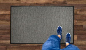 Aerial View of man standing on a Waterhog Classic Diamond carpet mat with standard rubber edges
