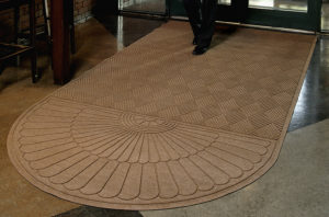Man walking on a Waterhog Grand Classic Entrance Mat with an oval on one end used as an indoor door mat to a hotel