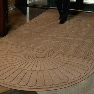 Man walking on a Waterhog Grand Classic Entrance Mat with an oval on one end used as an indoor door mat to a hotel
