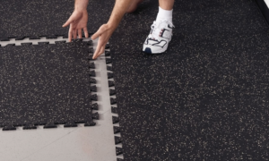 Man with 3/8" Interlocking Weight Room Flooring for Home Gyms showing easy Puzzle Interlock assembly